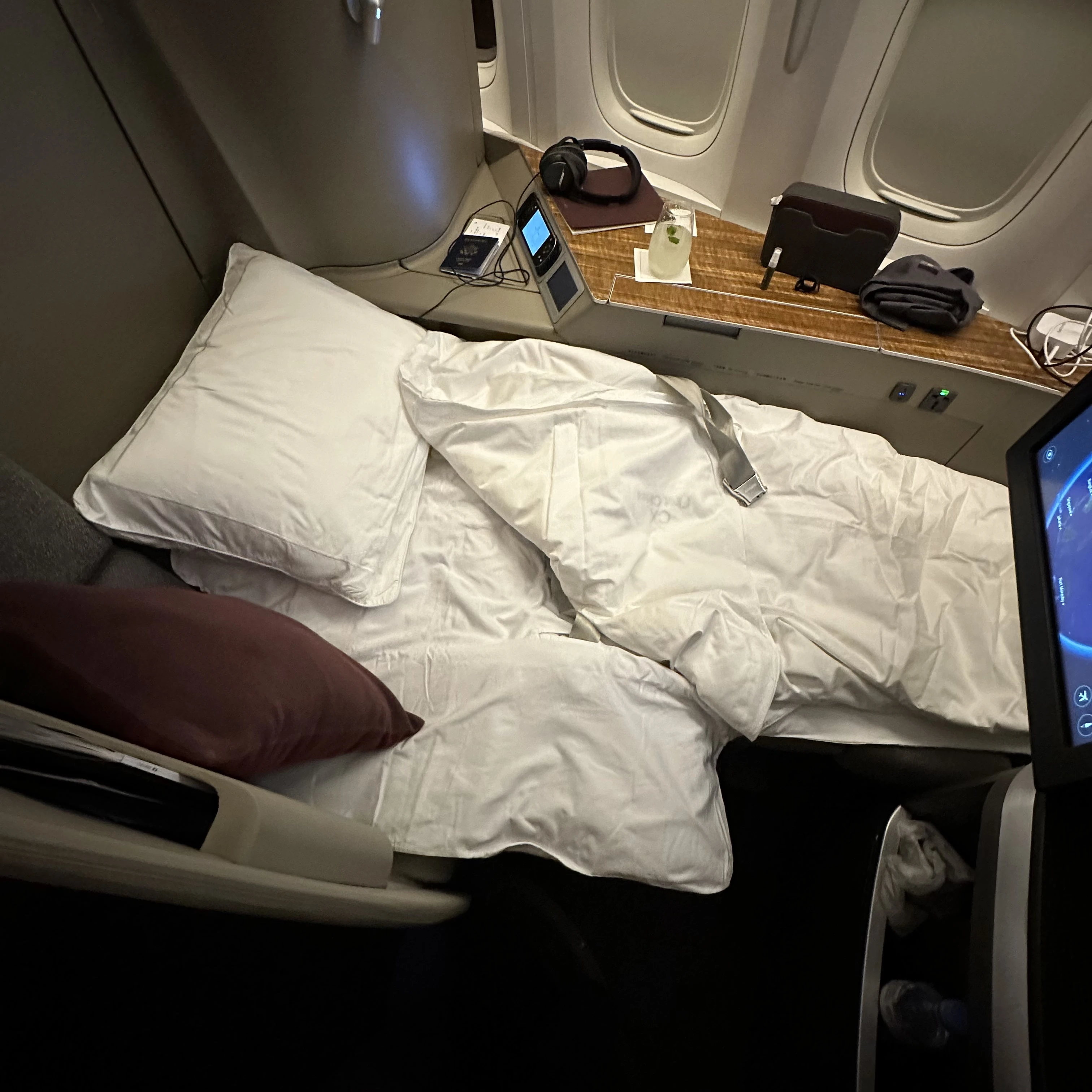 Cathay Pacific First Class lie-flat bed with luxurious bedding and mattress pad.