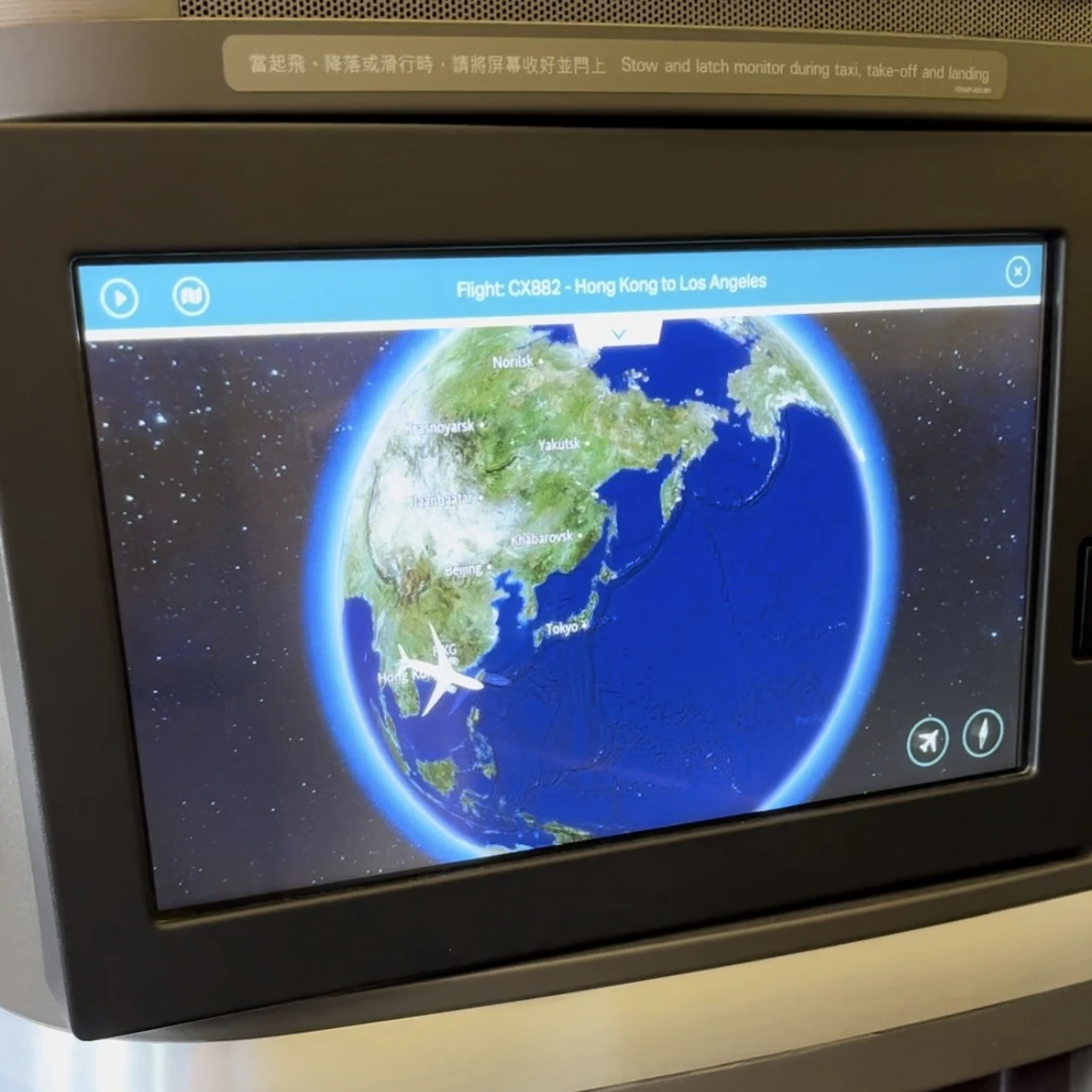 Cathay Pacific First Class entertainment system featuring a large TV screen.