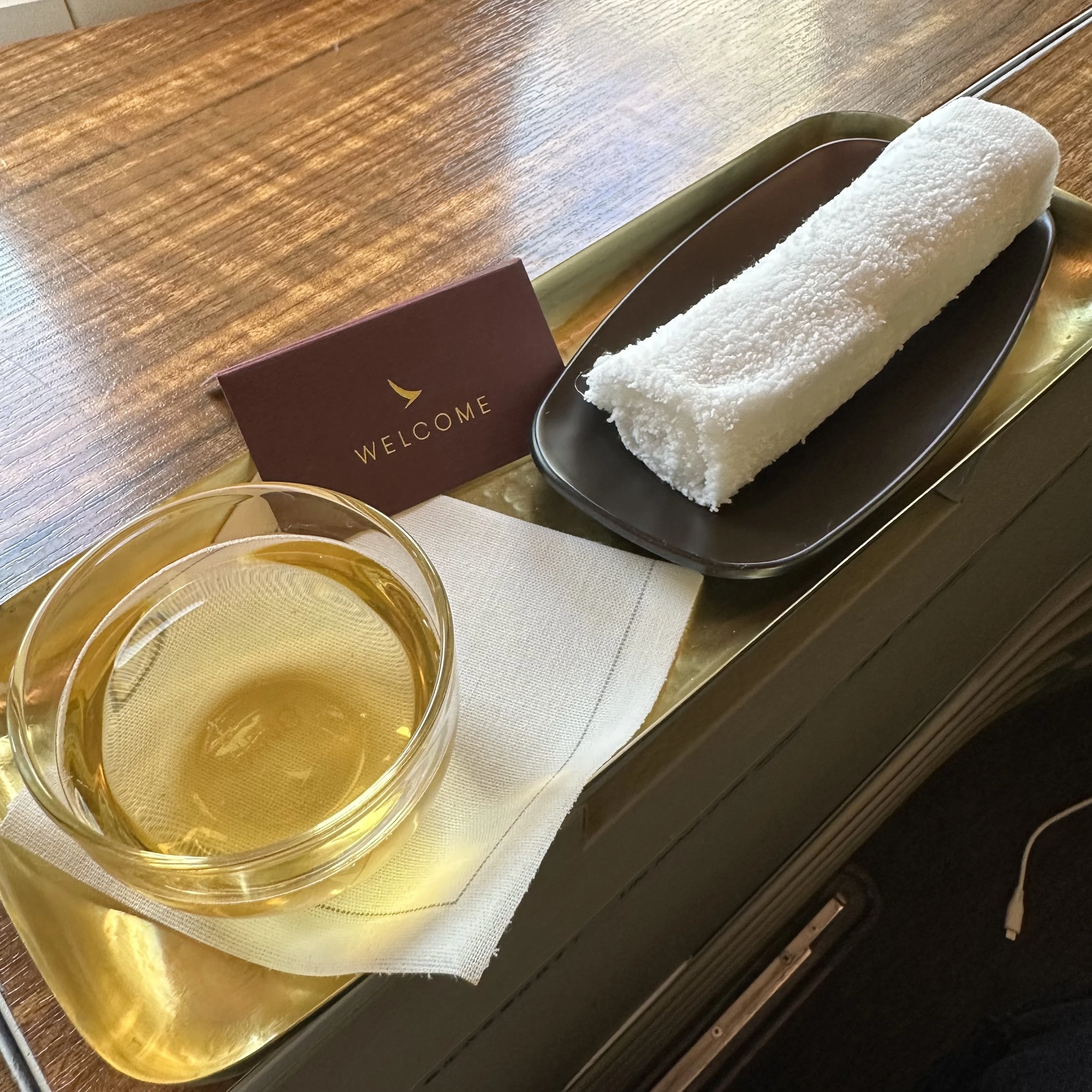 Cathay Pacific First Class welcome drink and hot towel for passengers before takeoff.