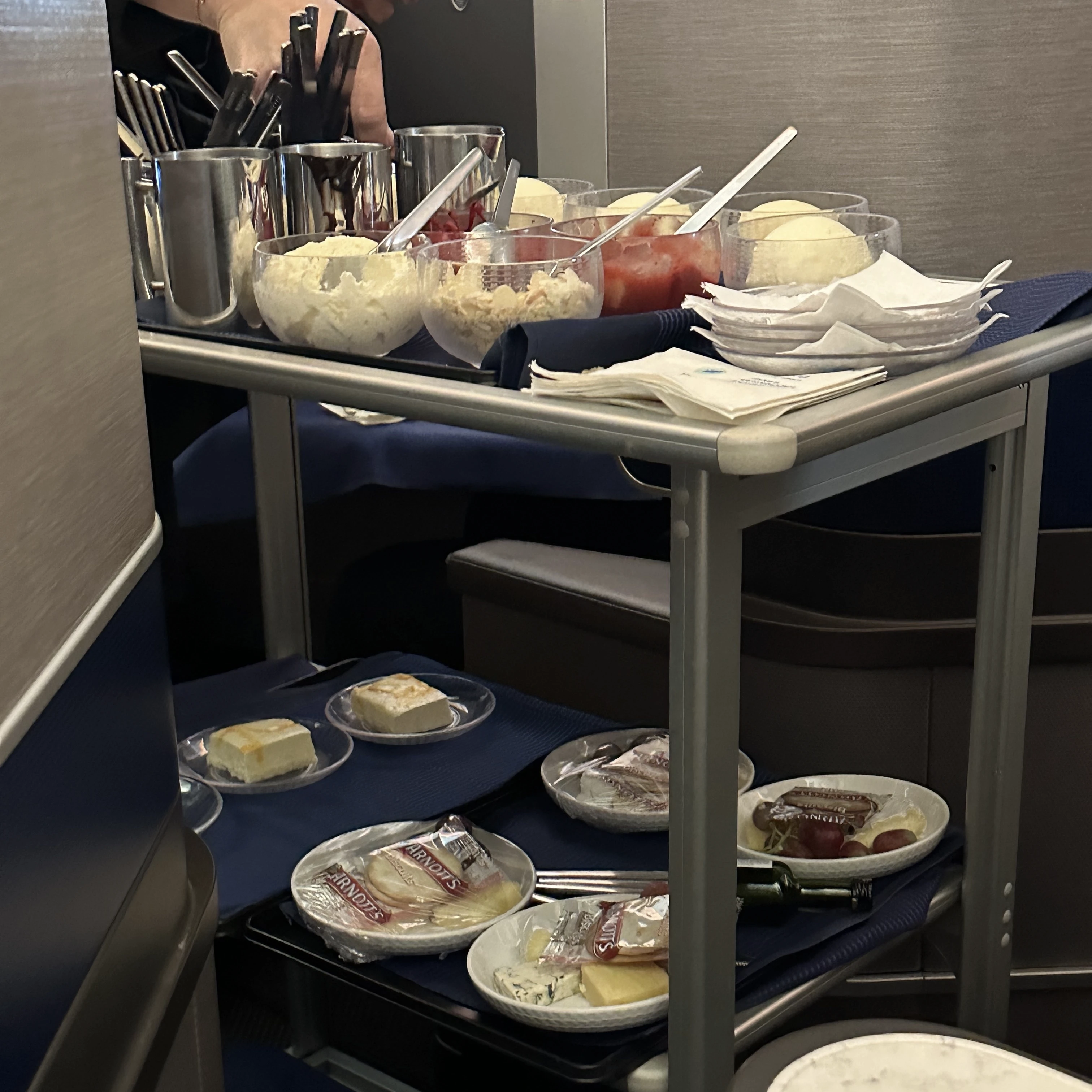 Ice cream sundae cart in United Polaris Business Class offering a variety of toppings for a personalized dessert.